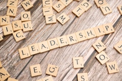 scrabble tiles spelling out the word leadership on a wooden surface