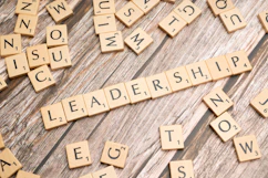 scrabble tiles spelling out the word leadership on a wooden surface