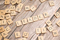 scrabble tiles spelling out the word leader in a word
