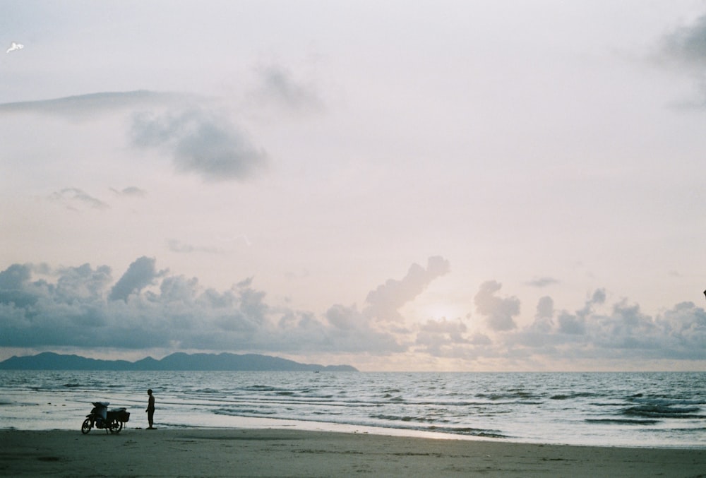 eine Person, die an einem Strand neben dem Meer steht