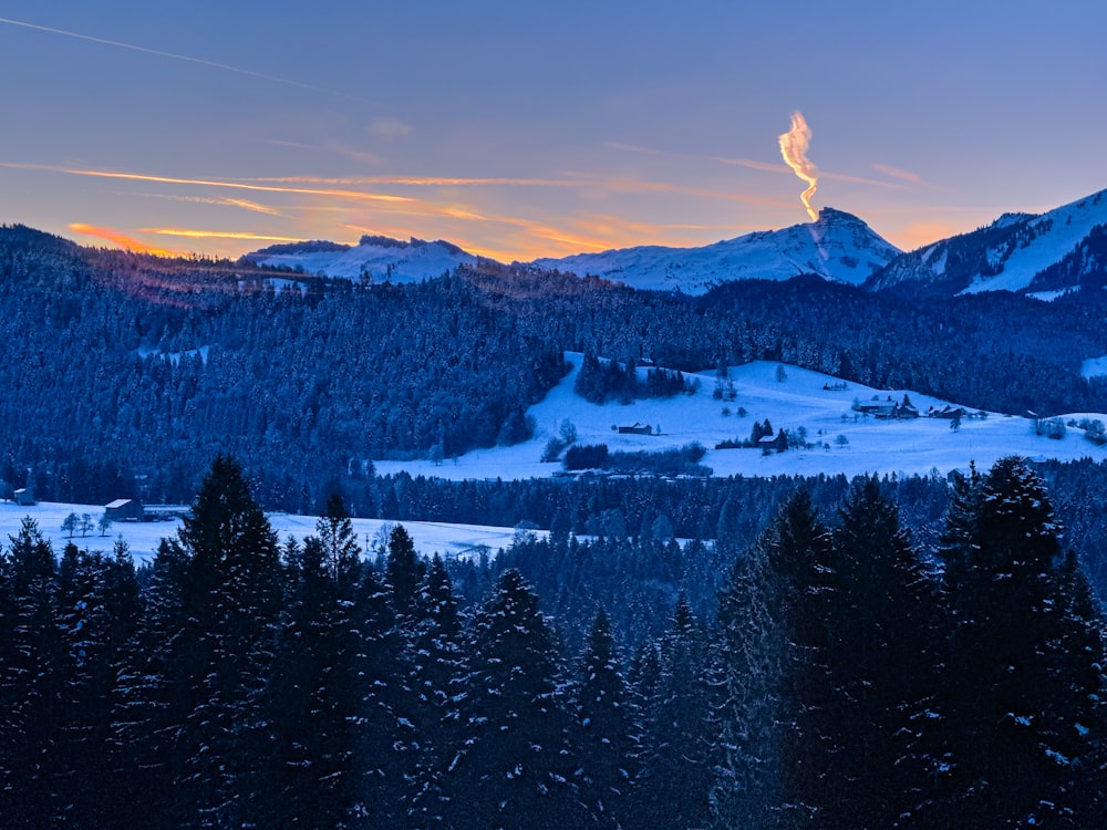 the sun is setting over a snowy mountain range