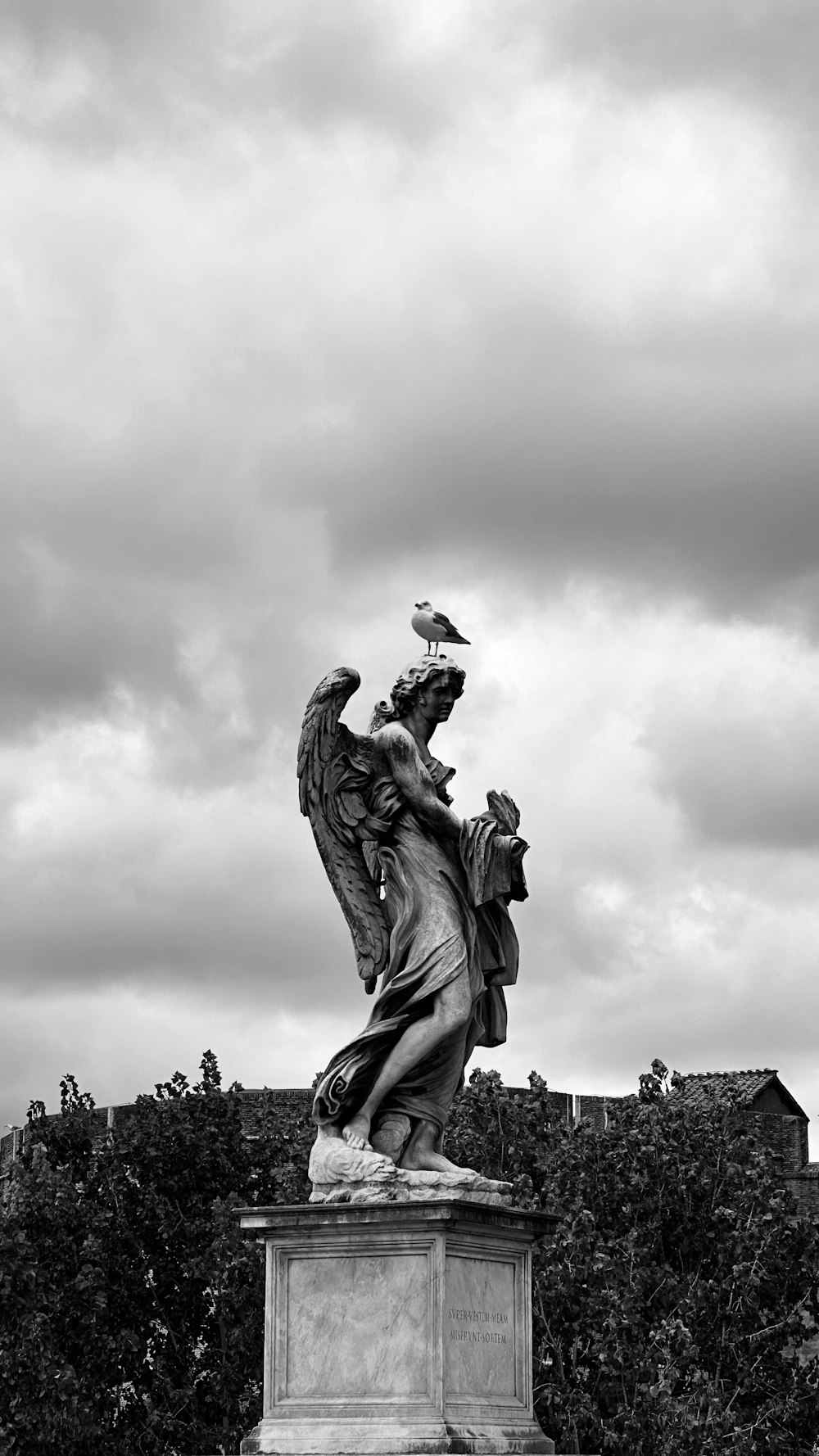 a black and white photo of a statue with a bird on top of it