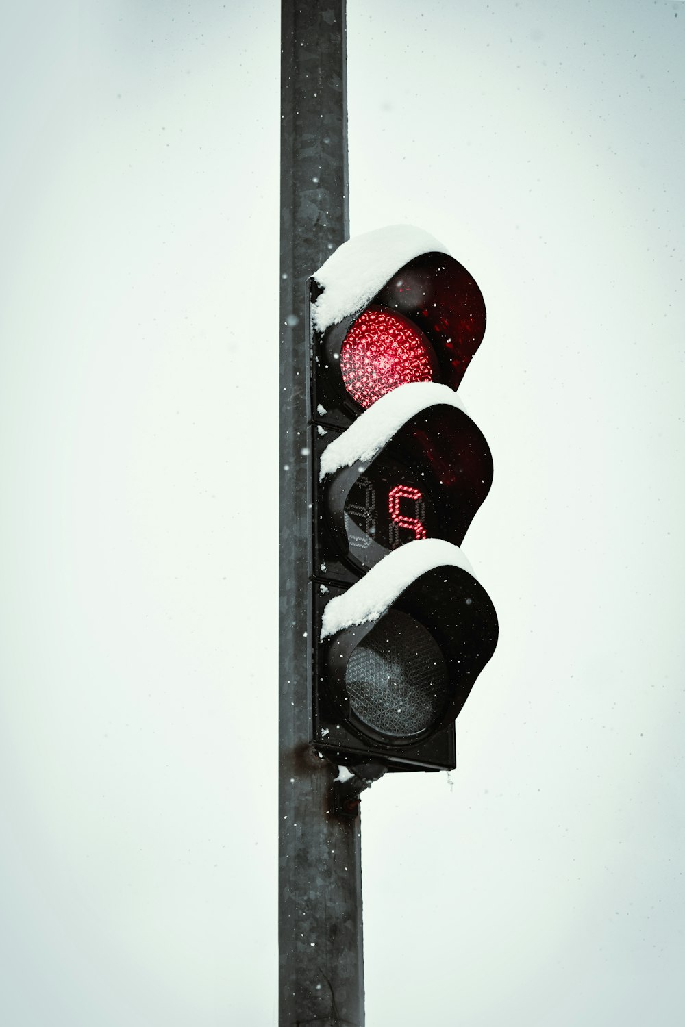 a traffic light with a red light in the snow