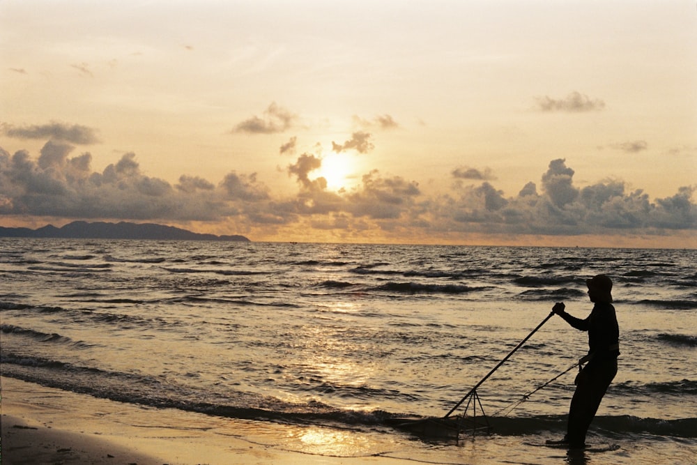 a man standing on top of a beach next to the ocean