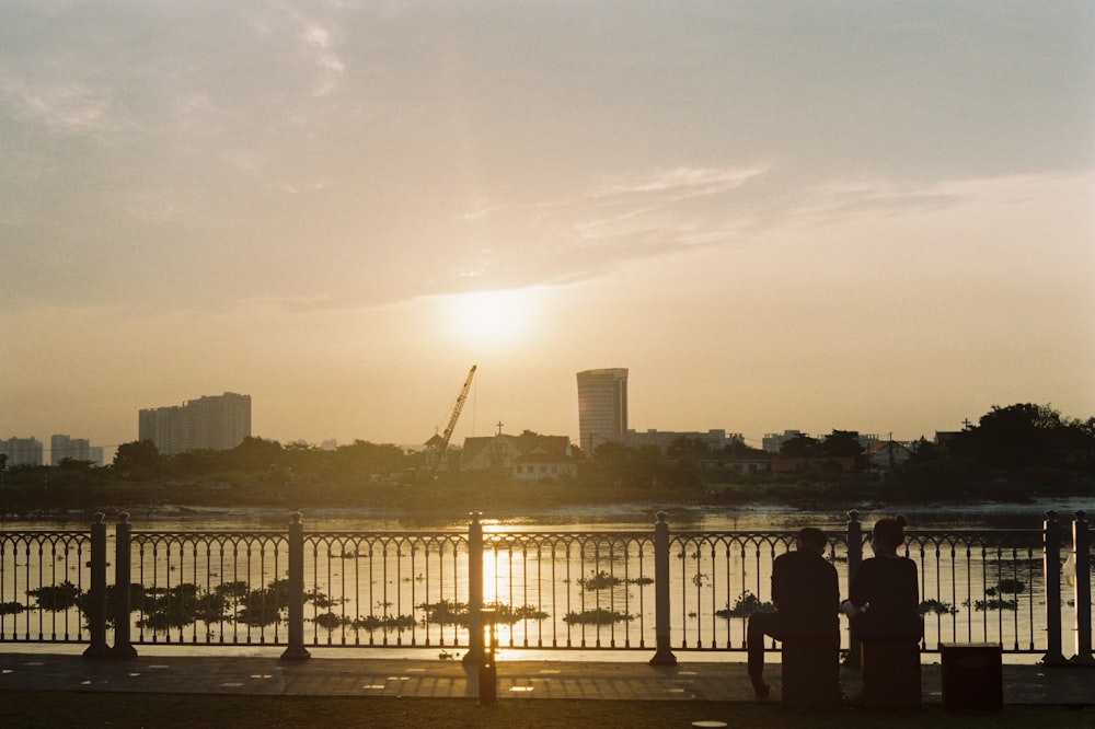 a couple of people sitting on a bench next to a body of water