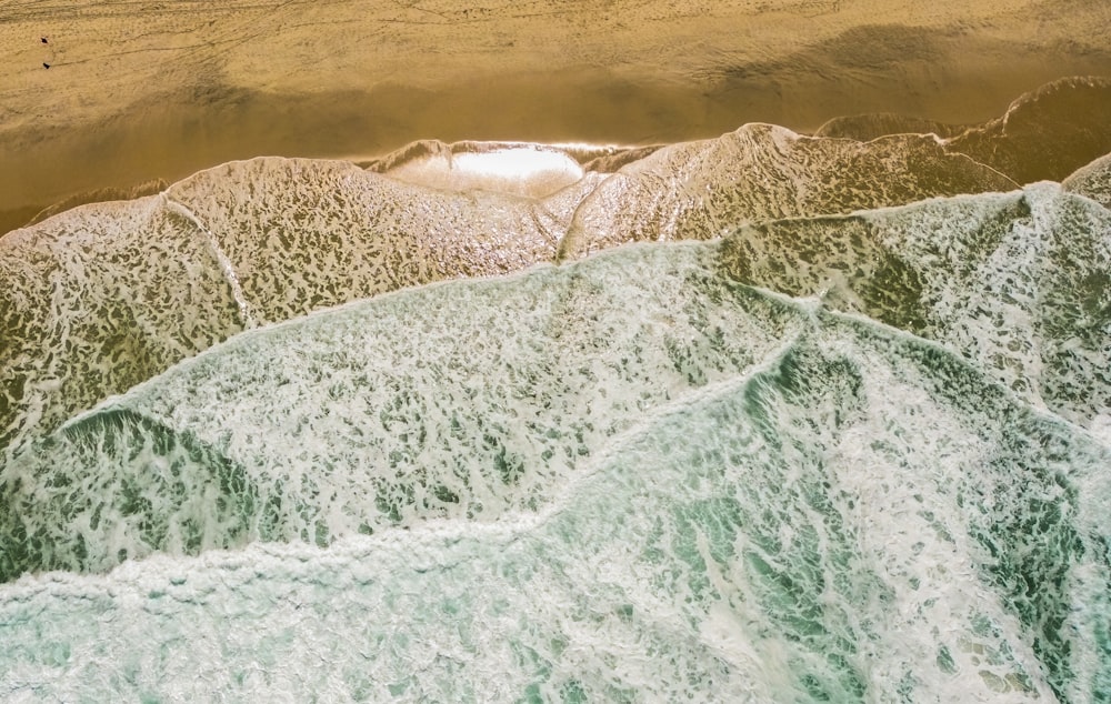 an aerial view of a beach with waves and sand