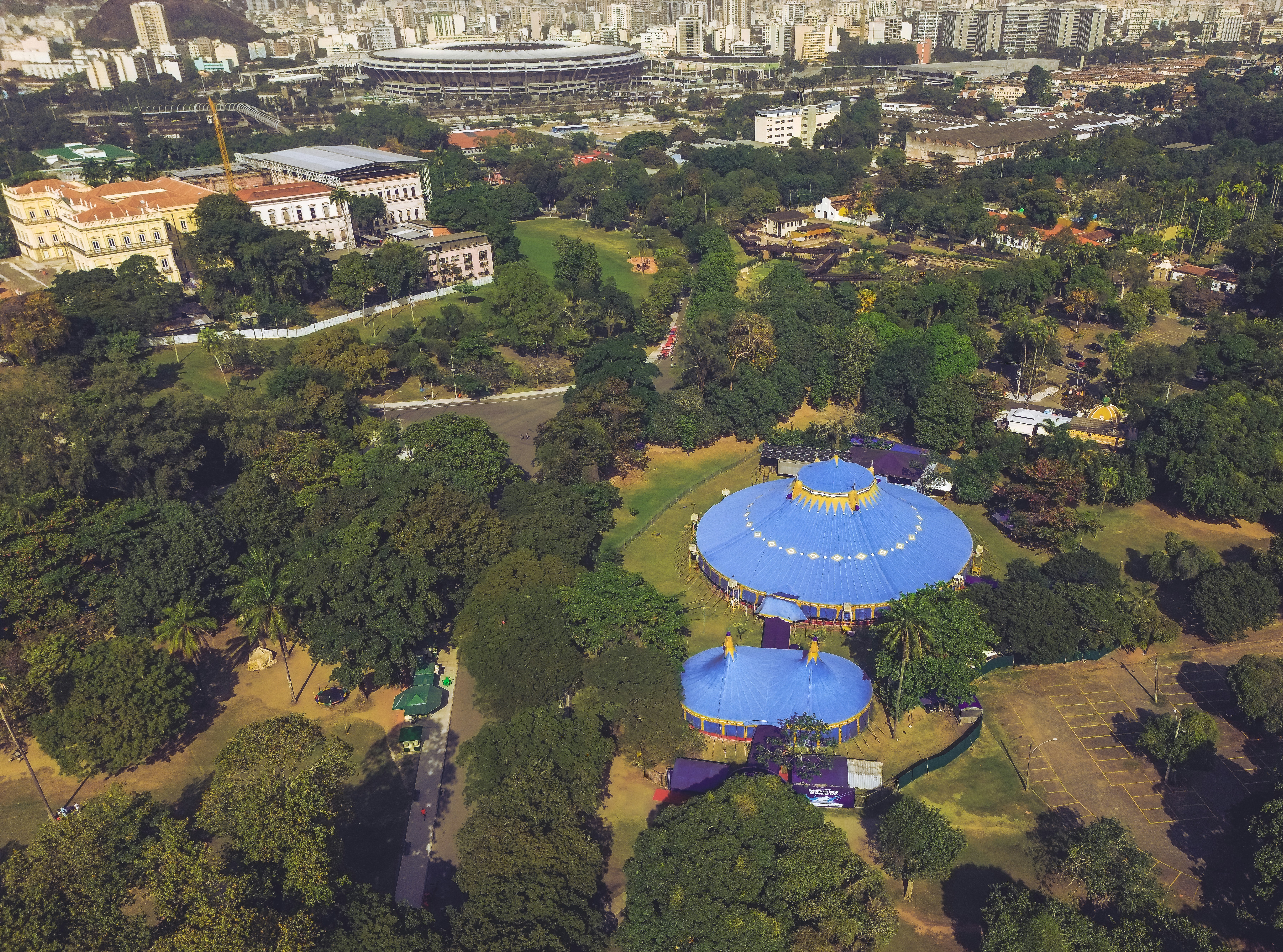 an aerial view of a park with trees and buildings in the background