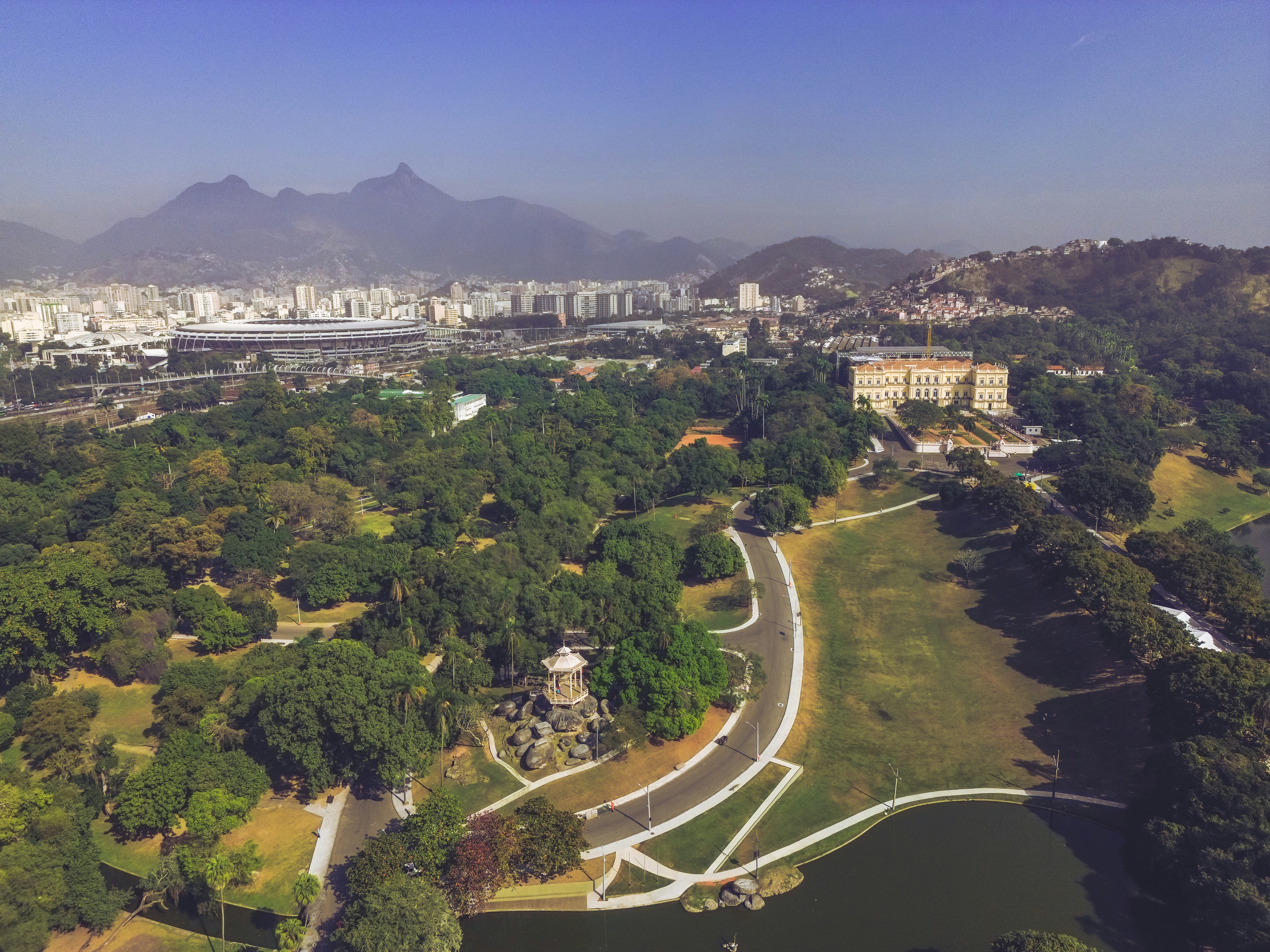 an aerial view of a park with a lake and mountains in the background