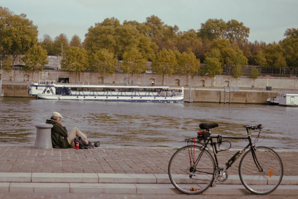 a man sitting on a bench next to a river