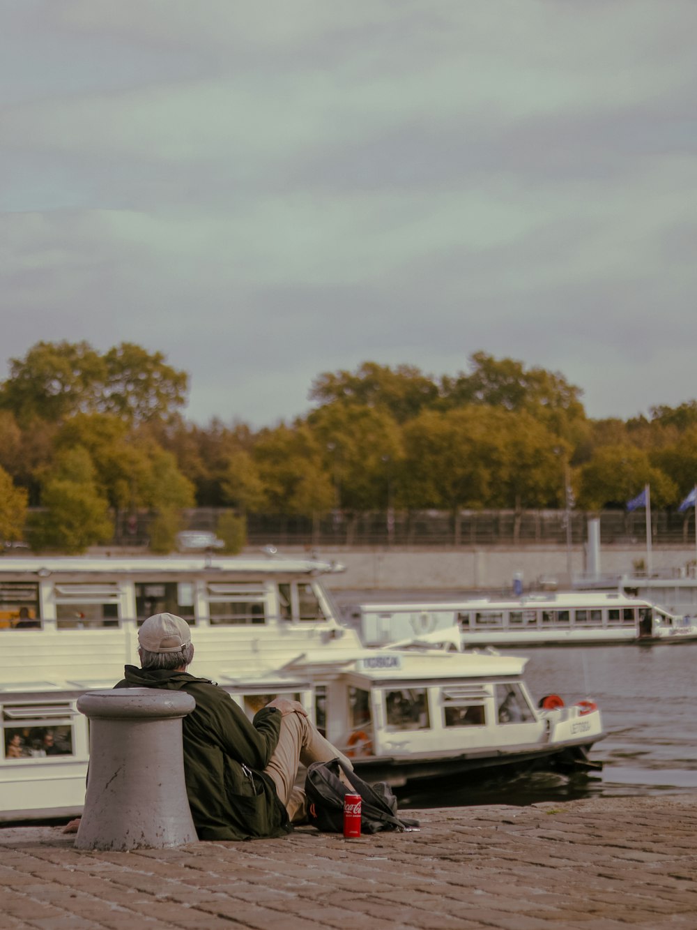 a man sitting on a bench next to a body of water