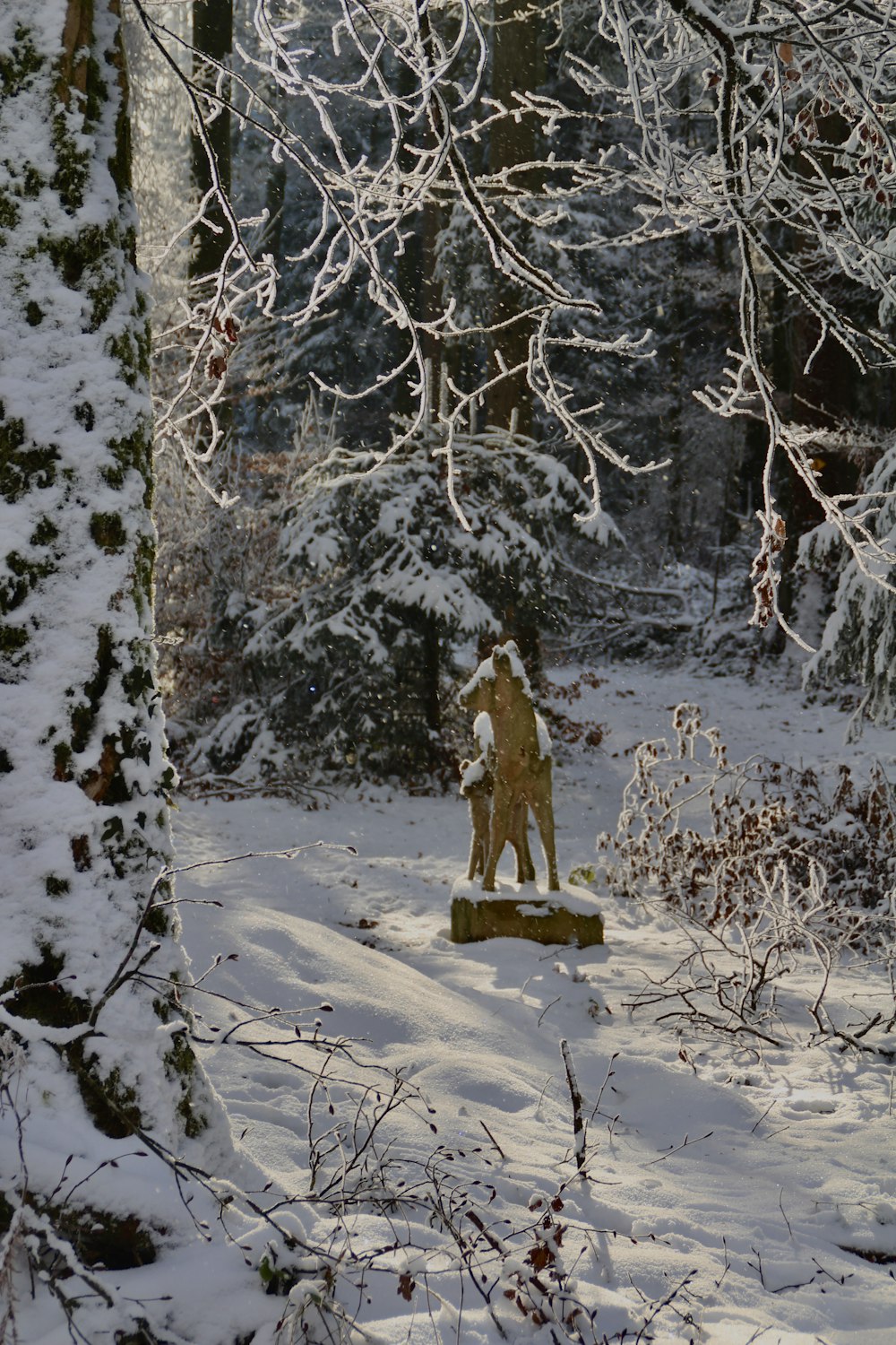 a statue in the middle of a snowy forest