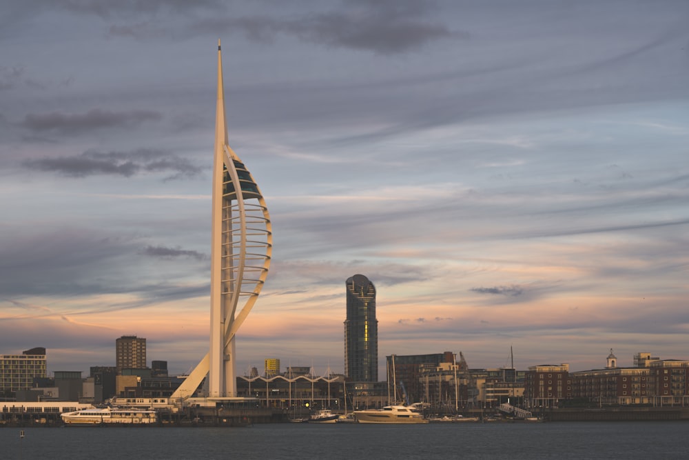 a tall tower with a spiral design on top of a body of water