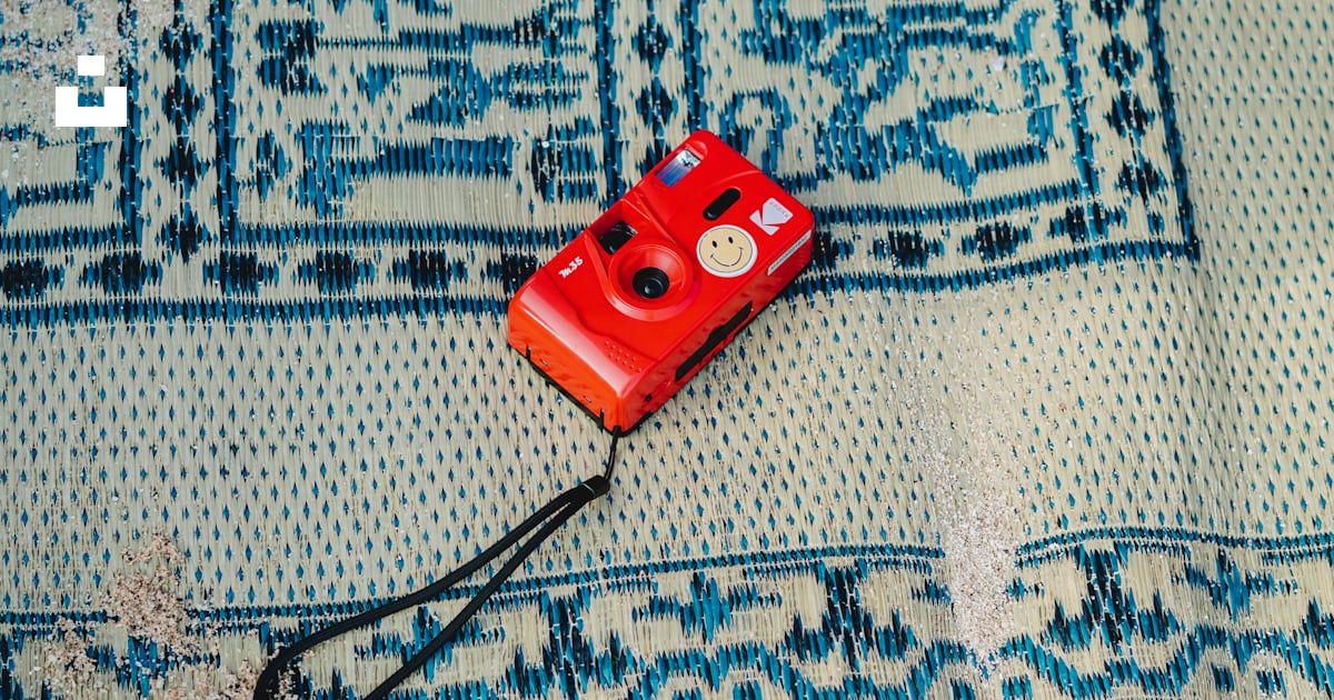 Un appareil photo rouge posé sur un tapis bleu photo – Image gratuite ...