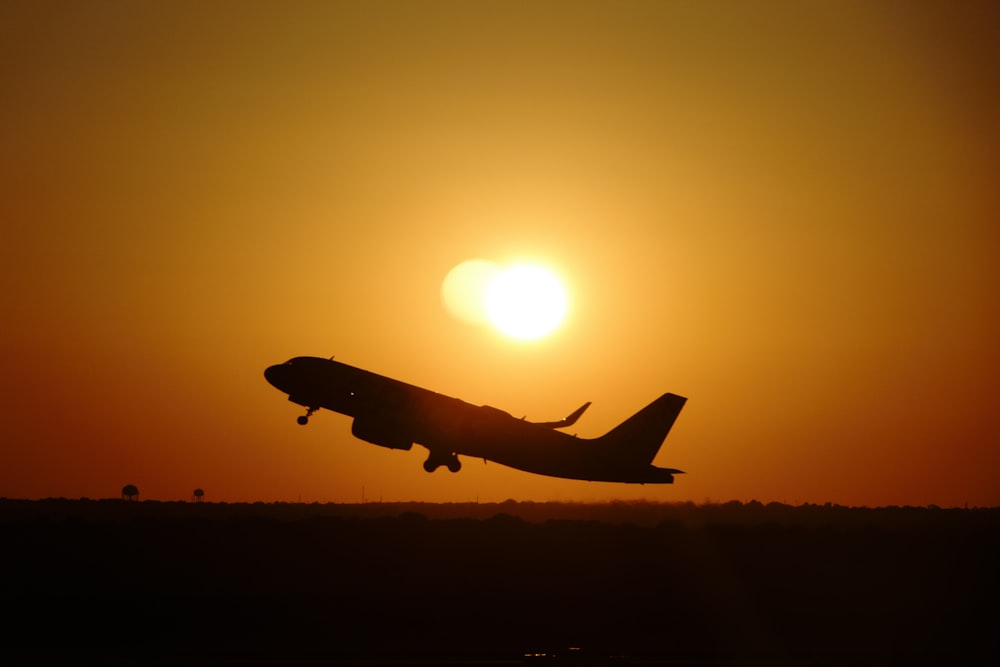 a plane flying in the air at sunset