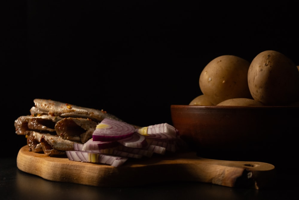 a wooden cutting board topped with meat and potatoes