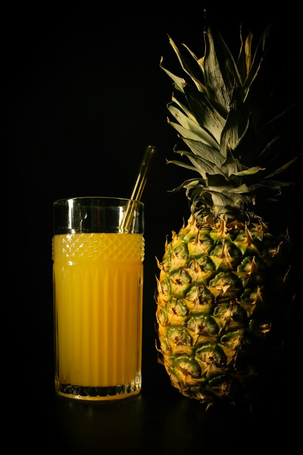 a glass of orange juice next to a pineapple