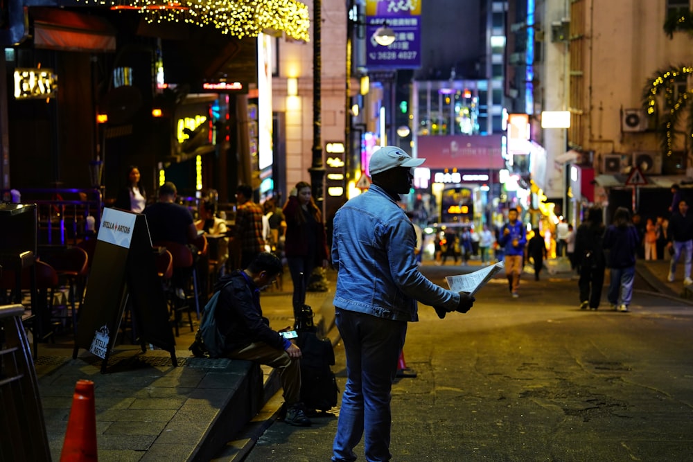 a man standing on the side of a street holding a piece of paper