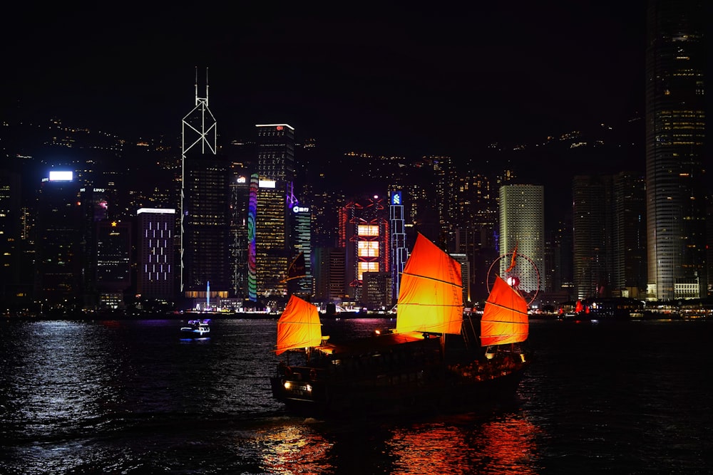 a boat with orange sails in a body of water