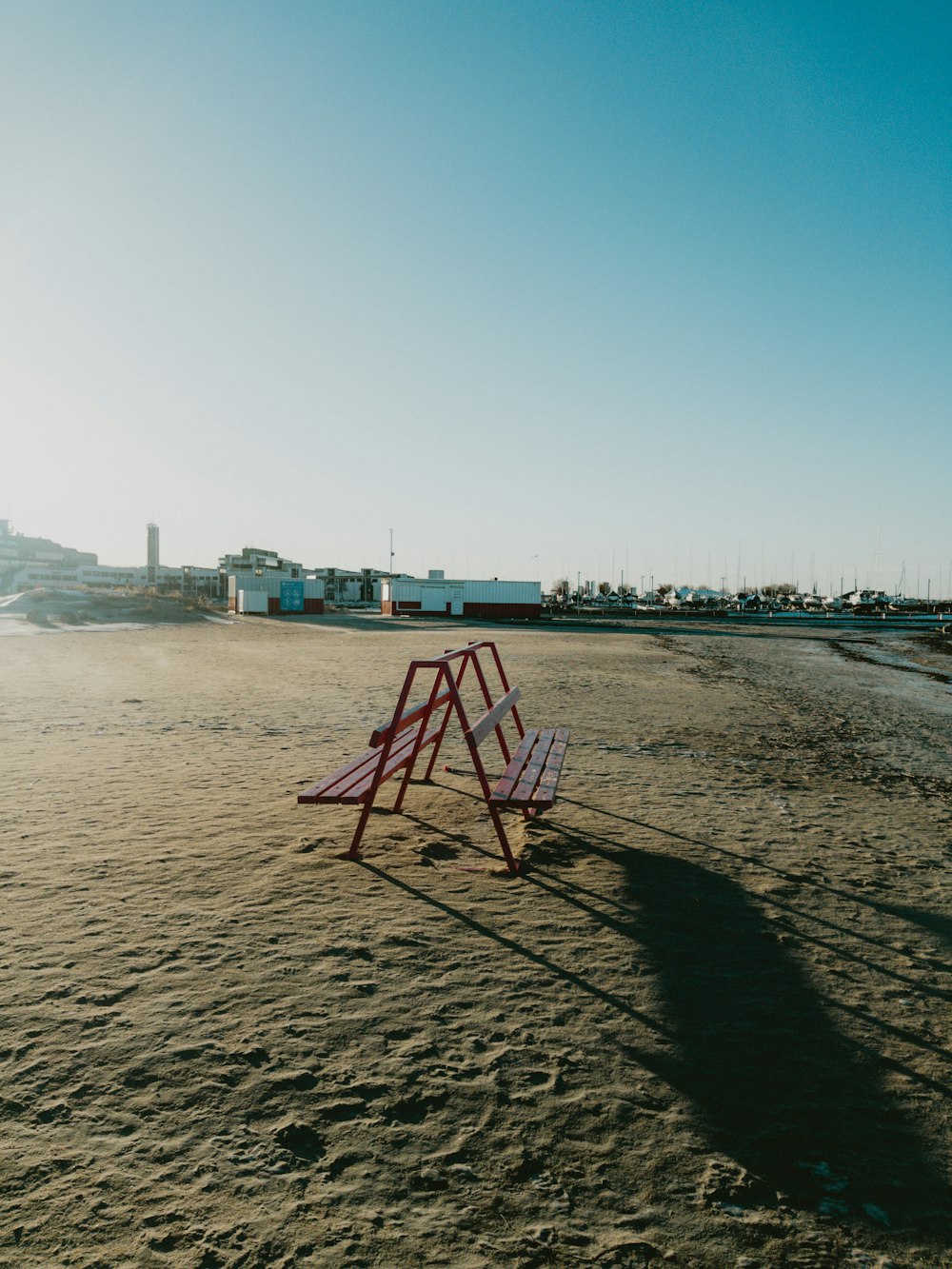 a red and white chair sitting on top of a sandy beach