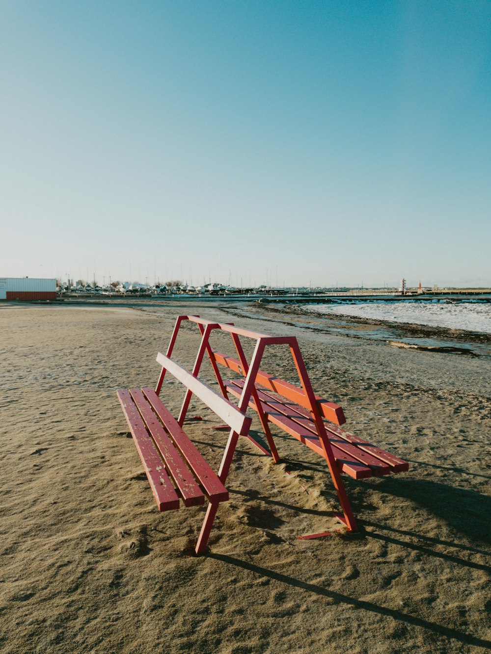 a wooden bench sitting on top of a sandy beach