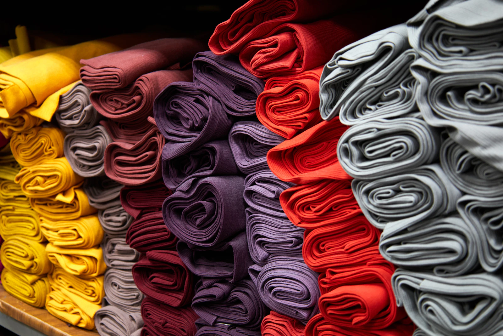 Folded fabric stacked and sorted by colour in a shop