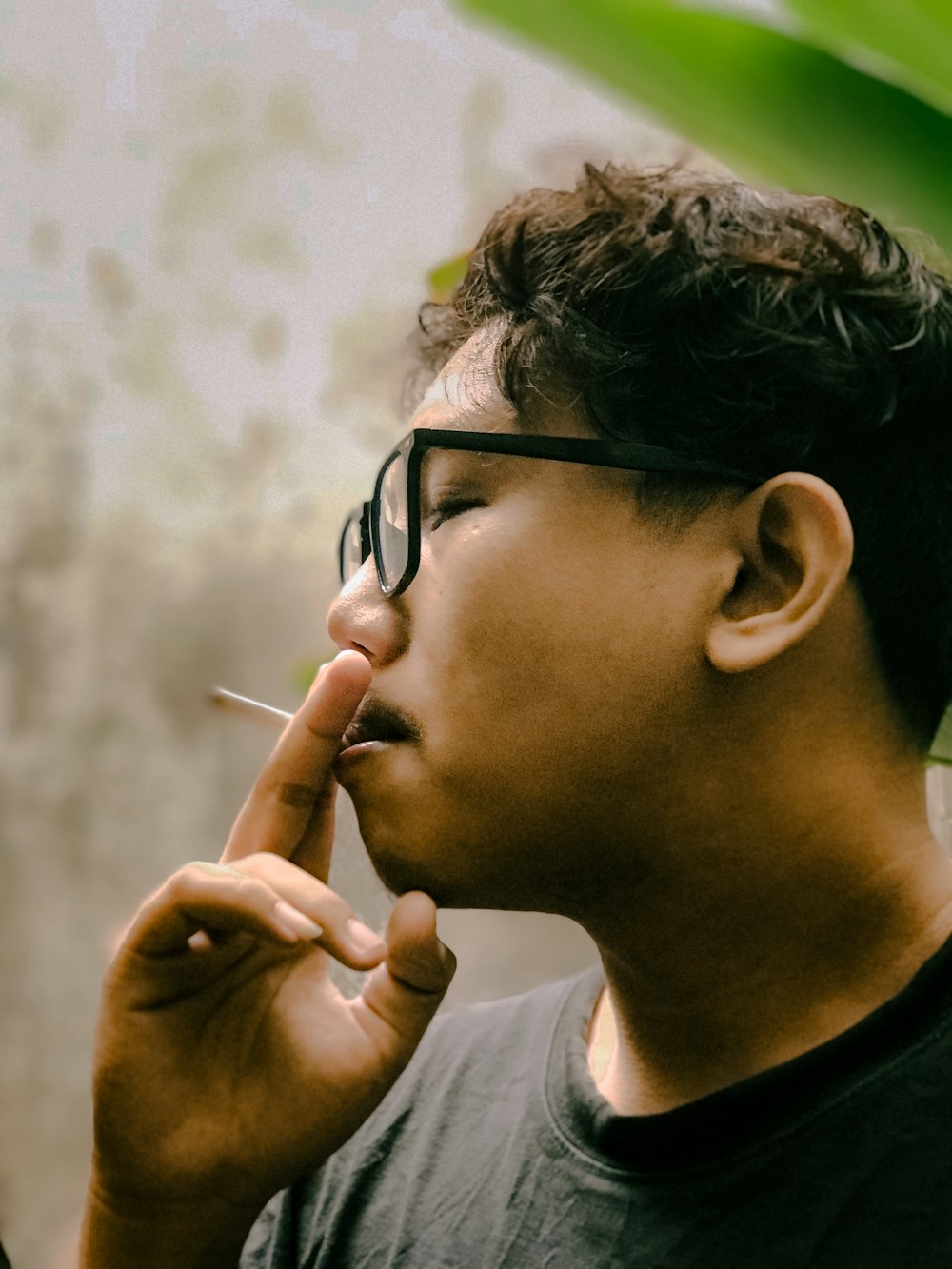 안경을 쓴 남자가 담배를 피우고 있다