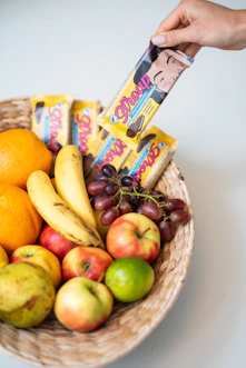 a basket filled with fruit and a hand holding a bar