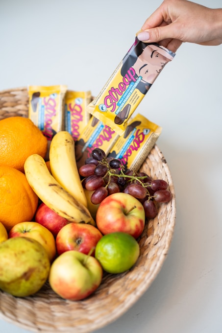 a basket filled with fruit and a hand holding a bar