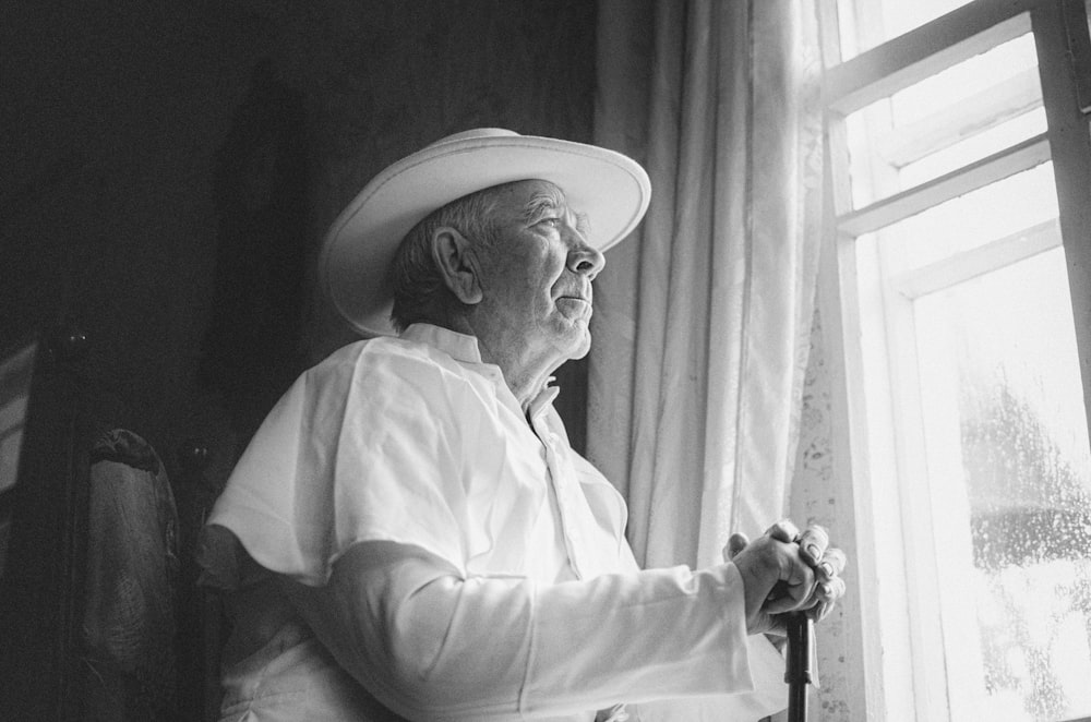 a black and white photo of an old man wearing a hat