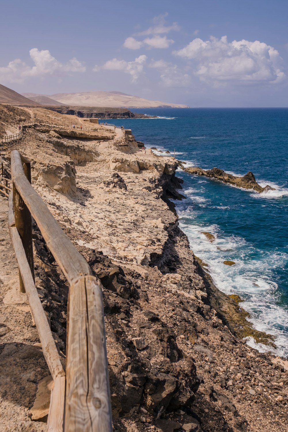 a wooden bench sitting on the side of a cliff next to the ocean