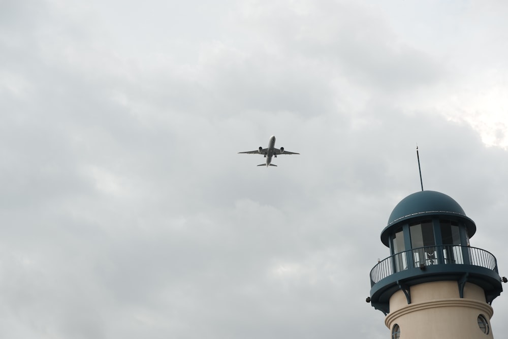 an airplane flying over a lighthouse on a cloudy day