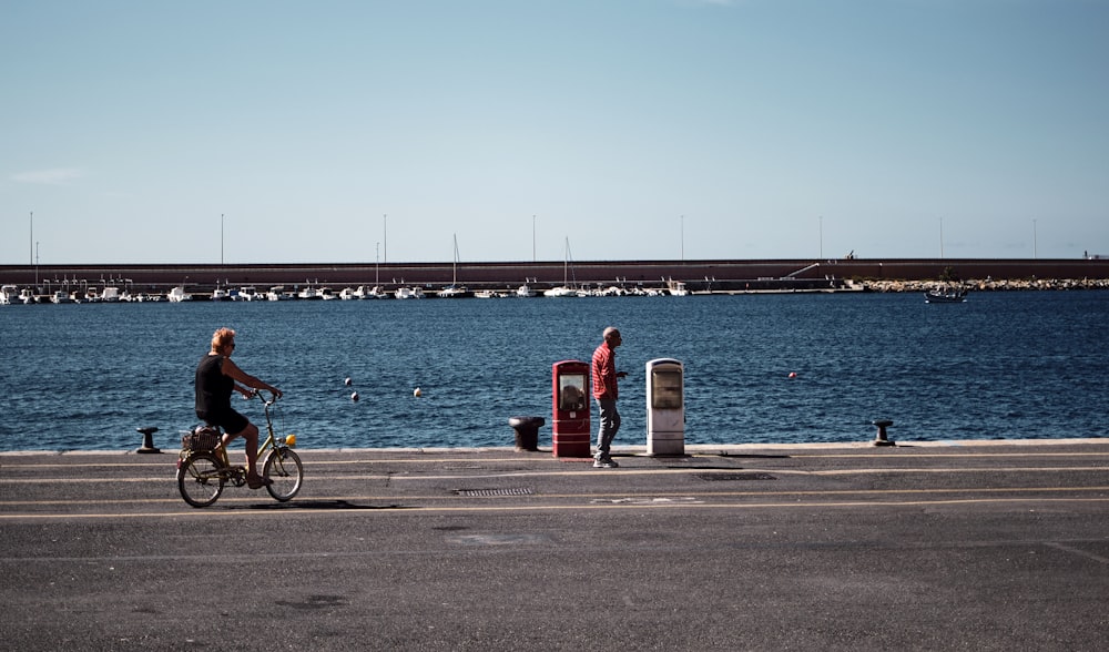 una persona montando en bicicleta junto a un cuerpo de agua