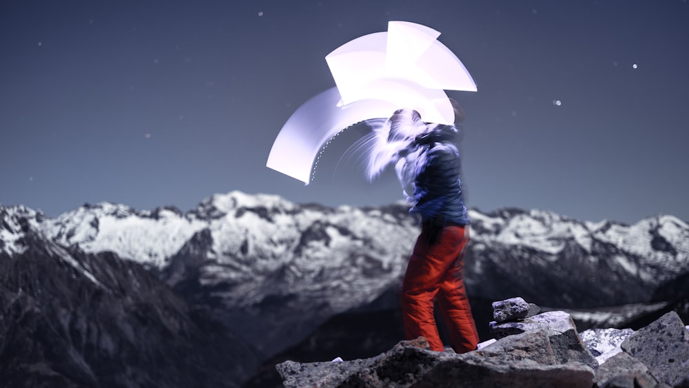 a person standing on top of a mountain holding an umbrella