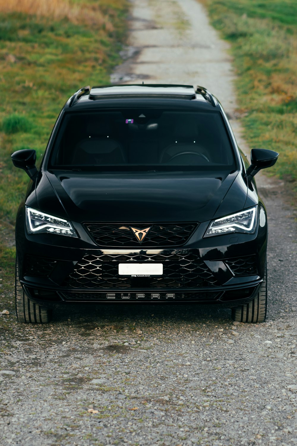 a black car parked on the side of a dirt road