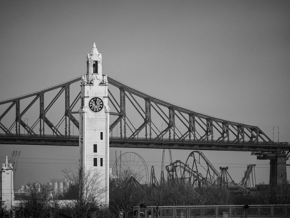 uma torre de relógio alta sentada sob uma ponte