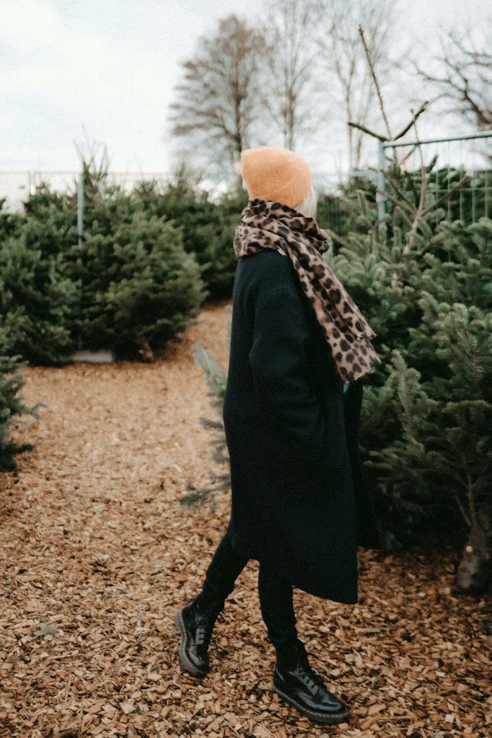 a woman walking through a christmas tree lot