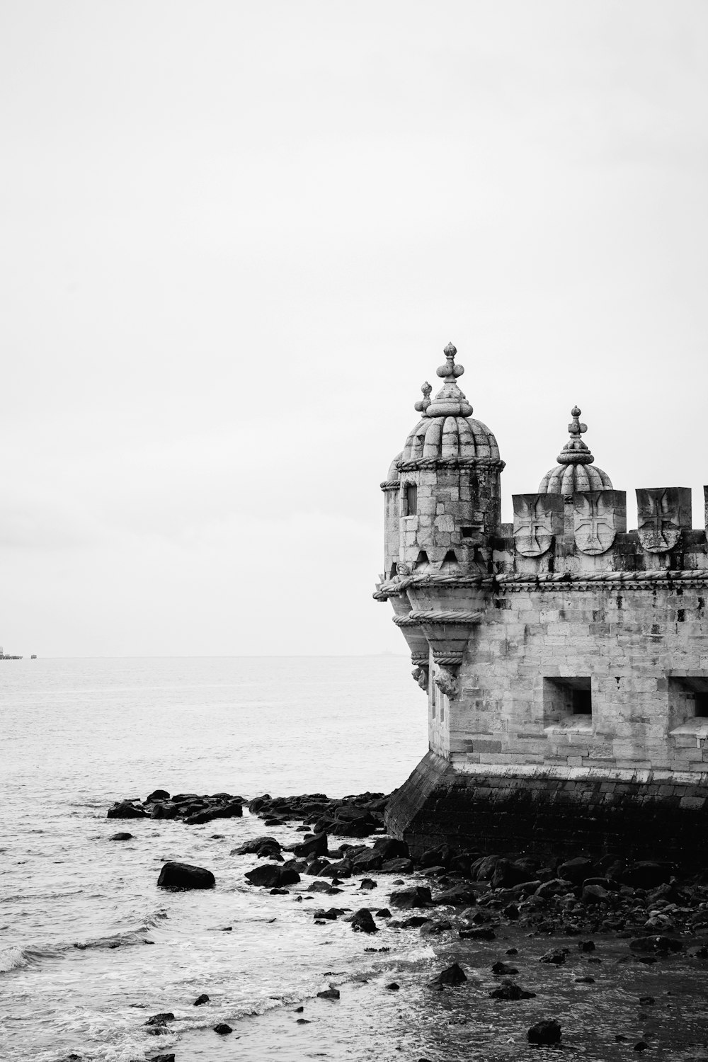 a black and white photo of a building near the ocean