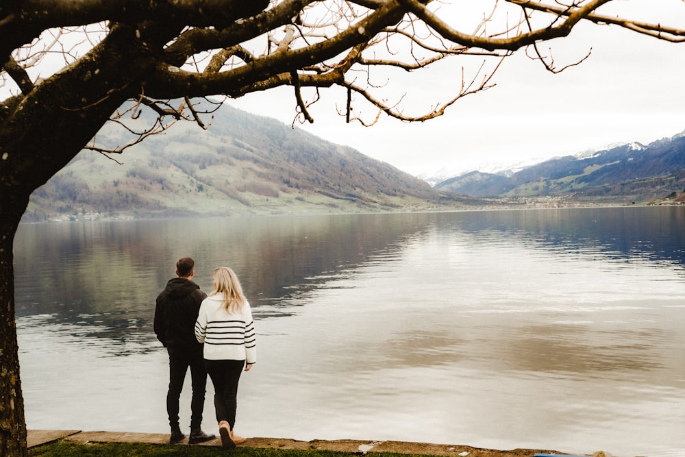 a man and a woman standing next to a lake