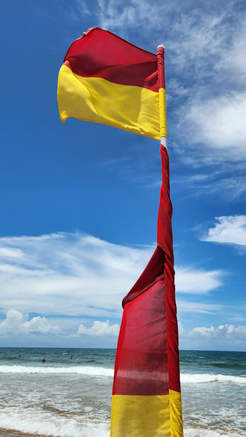 a red and yellow flag sticking out of the sand