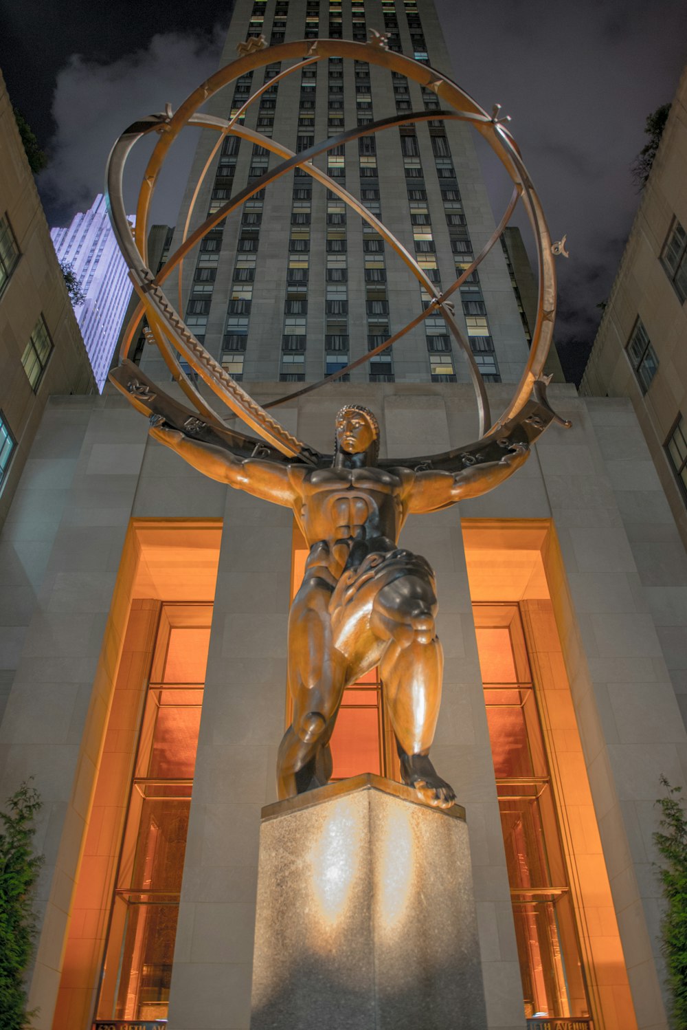 a statue of a man holding a globe in front of a building