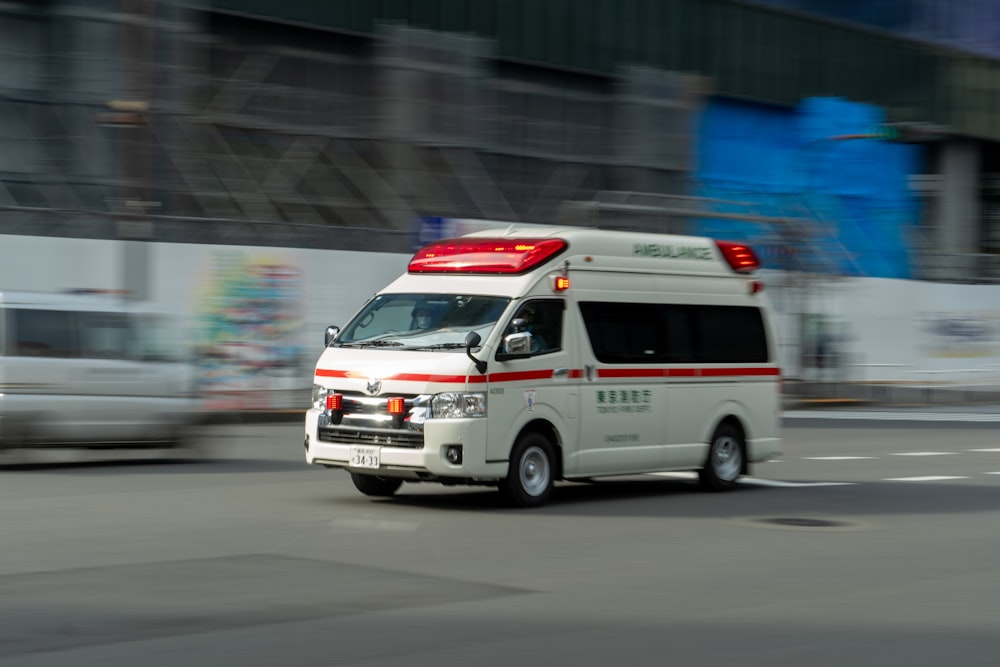 an ambulance driving down a street next to a building