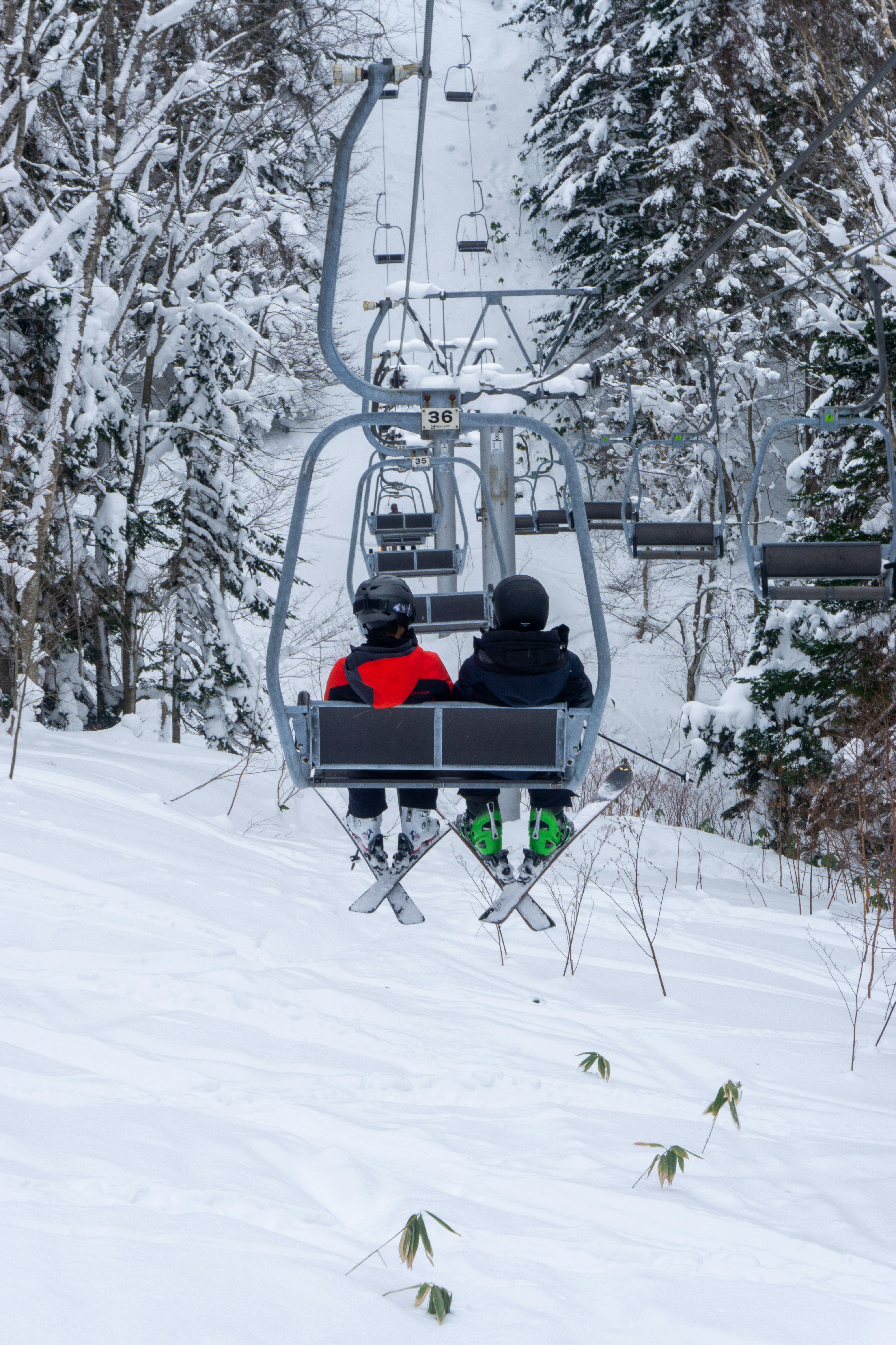 two people riding a ski lift in the snow