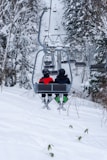 two people riding a ski lift in the snow