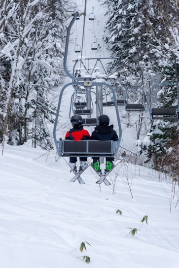 two people riding a ski lift in the snow