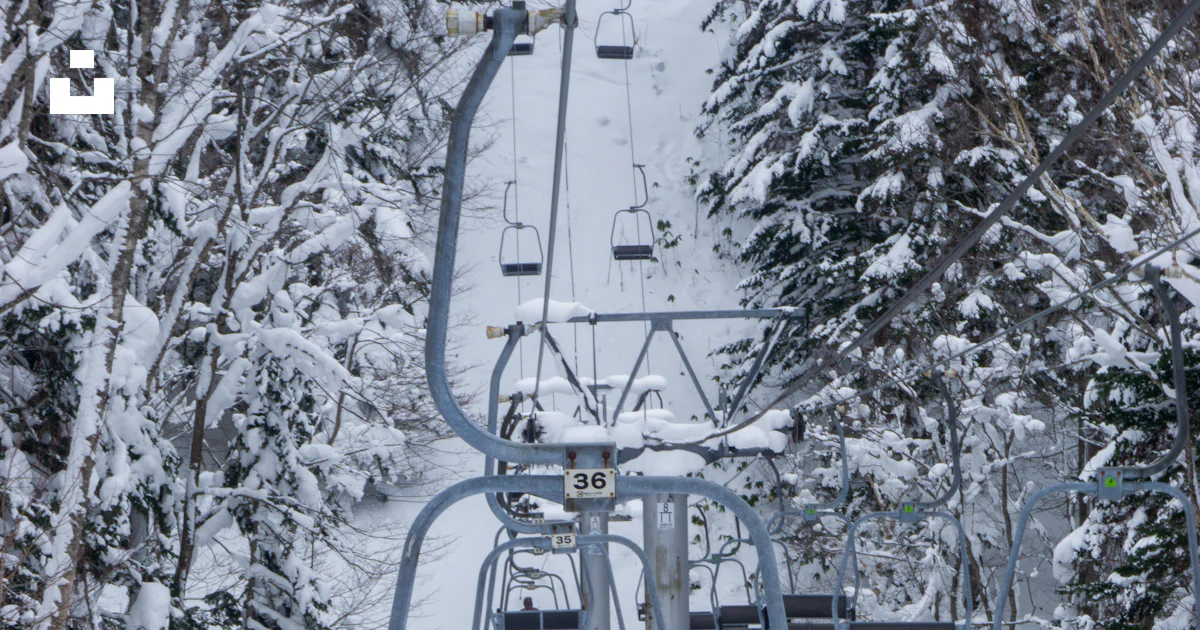 Two people riding a ski lift in the snow photo – Free Hokkaido Image on ...