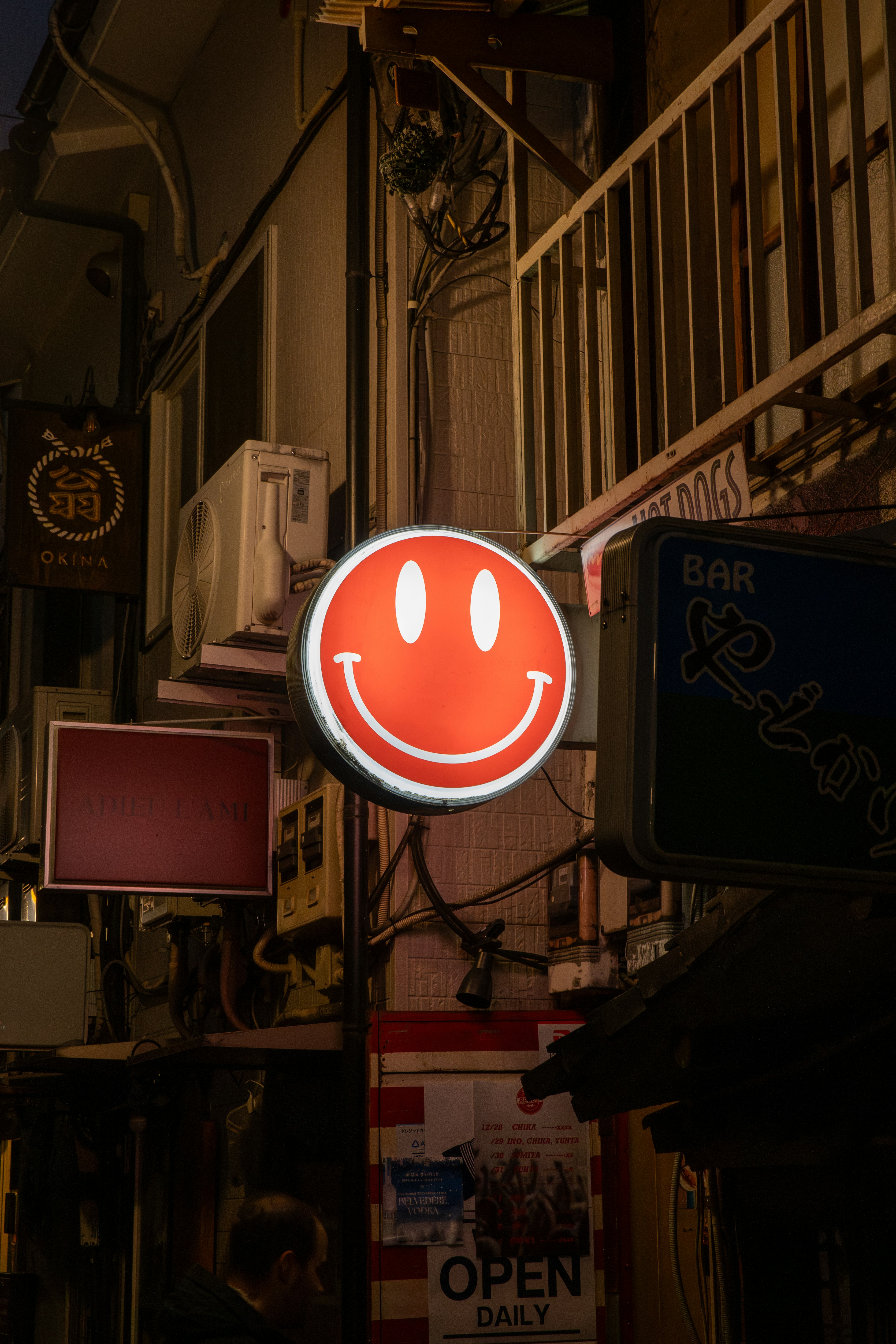 a red smiley face sign hanging from the side of a building