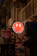 a red smiley face sign hanging from the side of a building