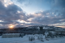 the sun is setting over a snowy mountain