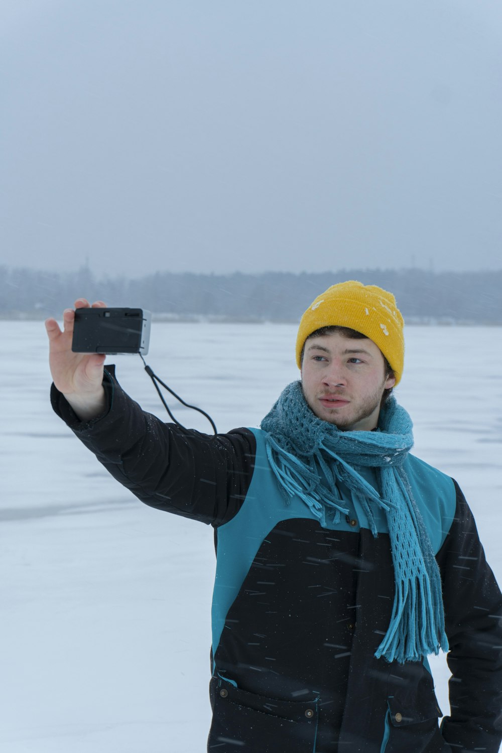 a man standing in the snow holding a camera
