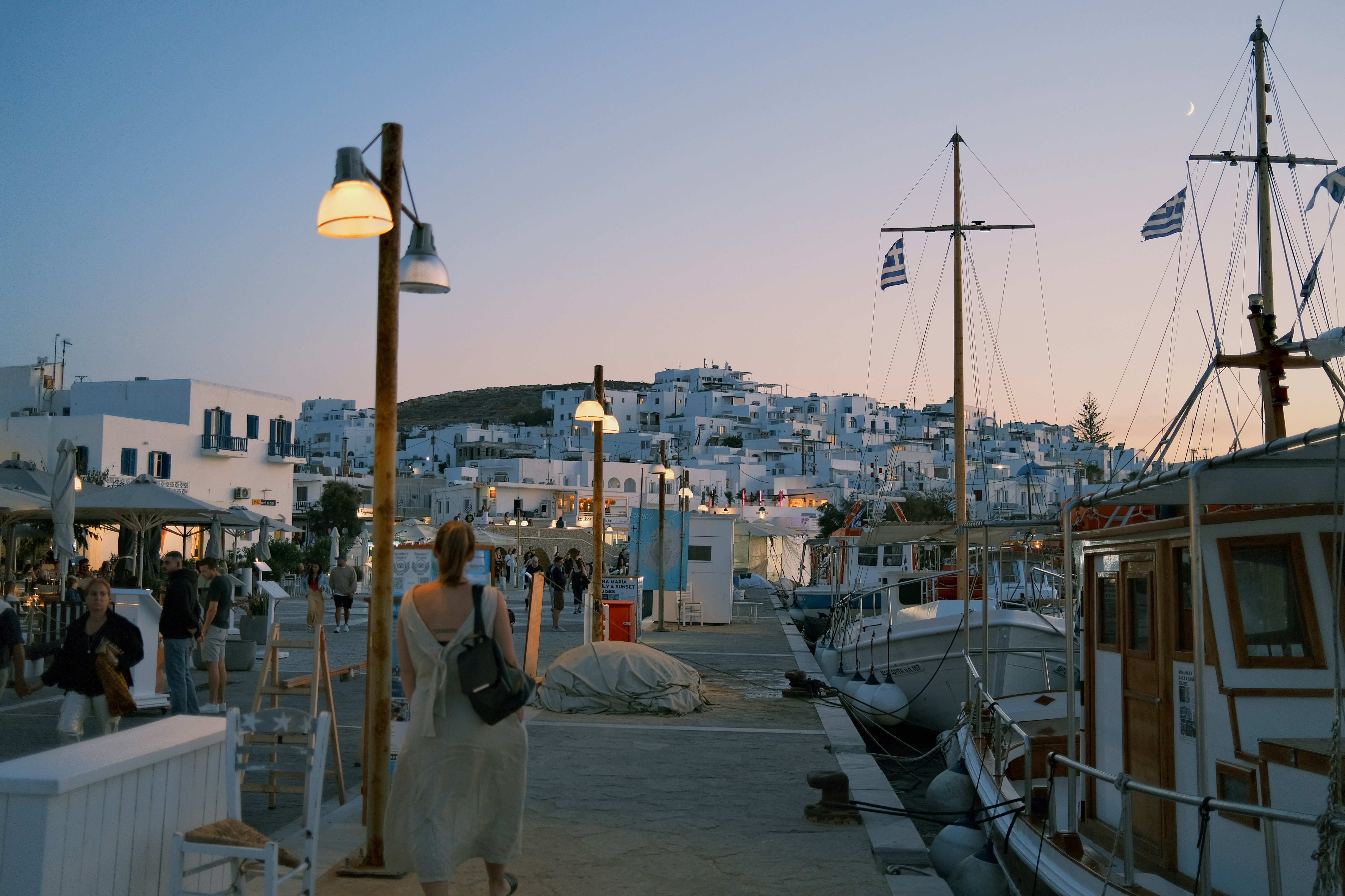 a group of people walking along a pier next to boats